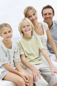 Portrait of happy kids with mature man and woman sitting by the beach